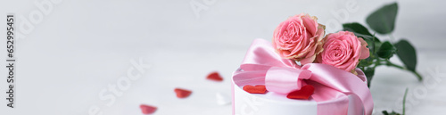 Beautiful surprise greeting for saint Valentine s or Women s Day  birthday or Anniversary for beloved. Fresh pink roses  gift box with sweets. White background. Holiday atmosphere. Banner copy space