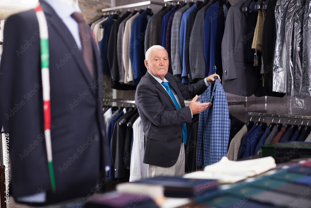 Elderly male shopper choosing fashionable blazer in a clothing store