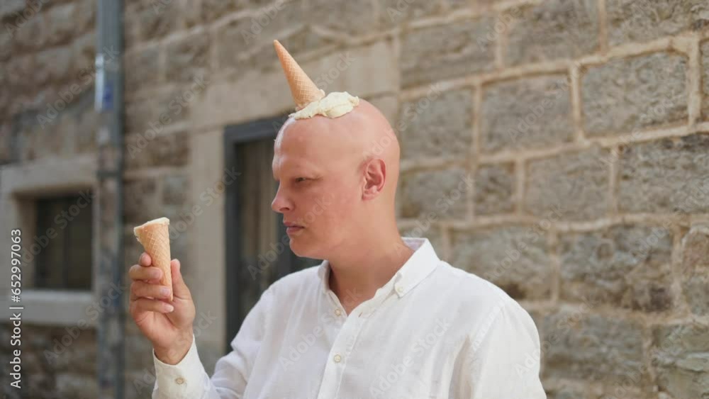Bald man with ice cream cones on his head , an ice cream mohawk