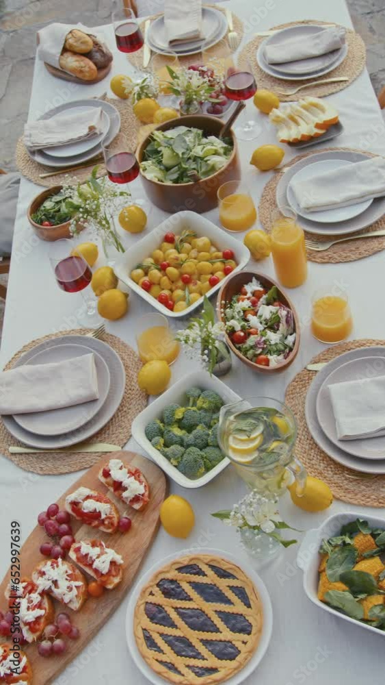 Vertical high angle no people shot of dining table set with delicious vegan dishes and decorated with flowers and lemons Vertical high angle no people shot of dining table set with delicious vegan dishes and decorated with flowers and lemons