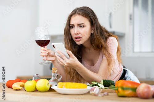 Upset woman texting on mobile phone in home kitchen