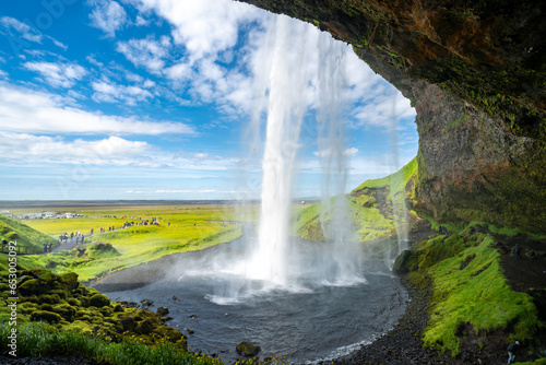 Breathtaking view behind the waterfall at Seljalandsfoss in Iceland on a sunny day