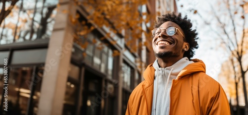 black person with glasses and afro hair looking up with yellow jacket and white sweatshirt laughing and very happy.