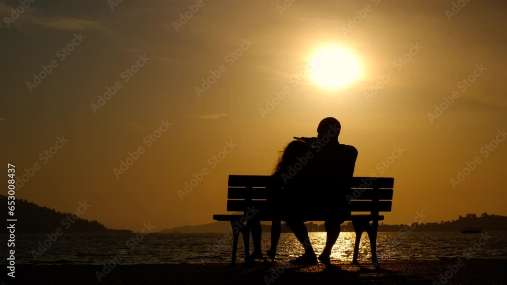 Man with daughter silhouette sitting on bench. Silhouettes of man with daughter show the evening sky on the bench in summer. A concept of fatherhood during childhood time. Man with daughter silhouette sitting on bench. Silhouettes of man with daughter show the evening sky on the bench in summer. A concept of fatherhood during childhood time.