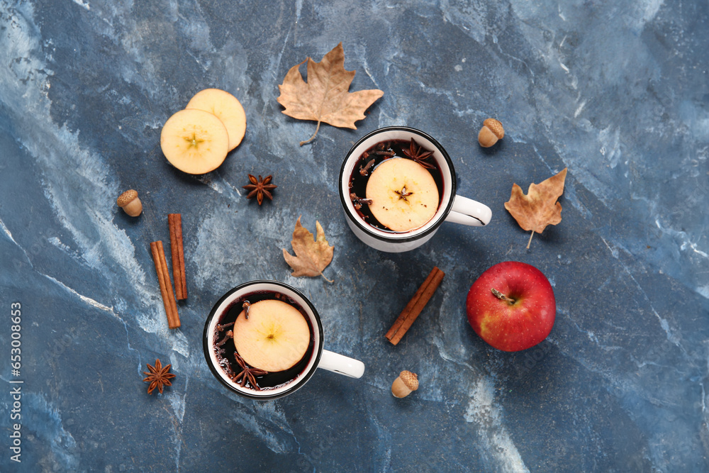 Cups of hot mulled wine with apple and cinnamon on blue background Cups of hot mulled wine with apple and cinnamon on blue background