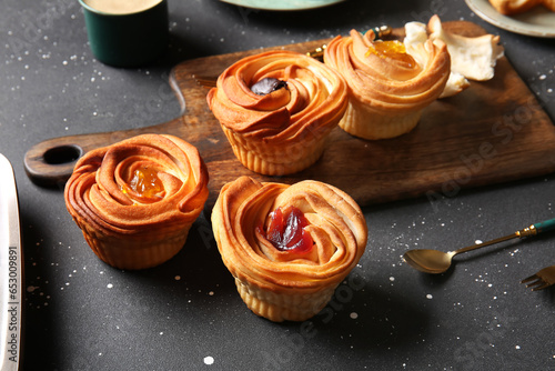 Wooden board of tasty cruffins with jam on black background photo