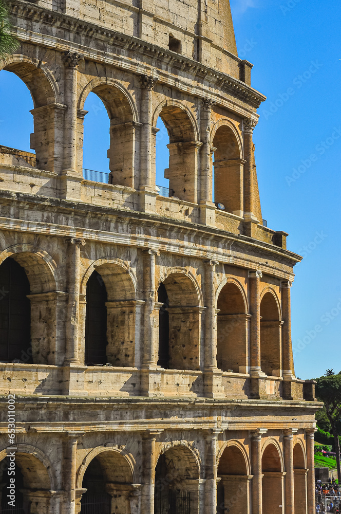 Front view, medium distance of, a section of, Roman Colosseum, against a clear, blue sky