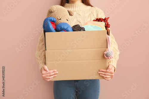 Woman holding box of unwanted stuff for yard sale on beige background photo