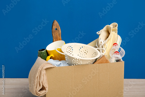 Box of unwanted stuff for yard sale on blue background photo
