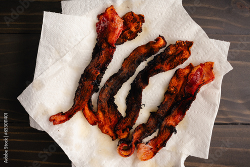 Overcooked Bacon Draining on Paper Towels: Strips of burned thick cut streaky bacon draining on kitchen roll photo