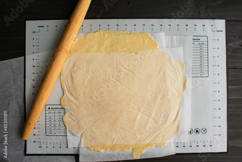 Rolling Out Pie Dough Between Sheets of Parchment Paper: Pie dough rolled out with a bamboo French rolling pin on a silicone mat photo