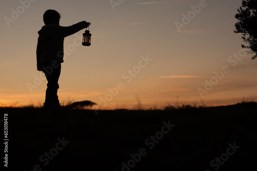 Christmas child silhouette at dusk with lantern. Winter. Horizontal. Copy space.