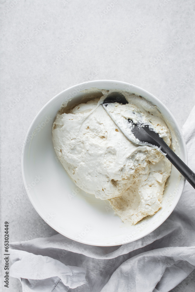 Strained Greek yogurt in a white ceramic bowl, process of making Greek yogurt, strained thick yogurt in white mixing bowl Strained Greek yogurt in a white ceramic bowl, process of making Greek yogurt, strained thick yogurt in white mixing bowl