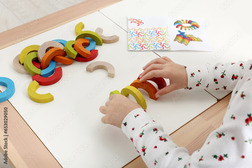 Fototapeta premium Motor skills development. Girl playing with colorful wooden arcs at white table indoors, closeup