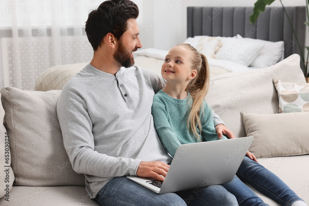 Happy man and his daughter with laptop on sofa at home Happy man and his daughter with laptop on sofa at home