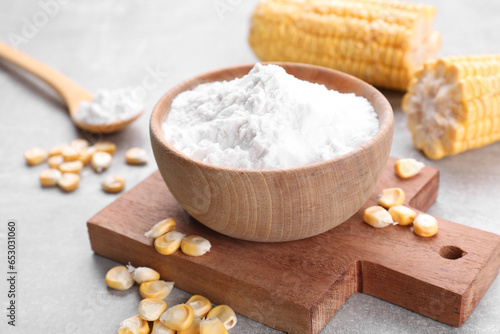 Bowl with corn starch and kernels on light grey table, closeup