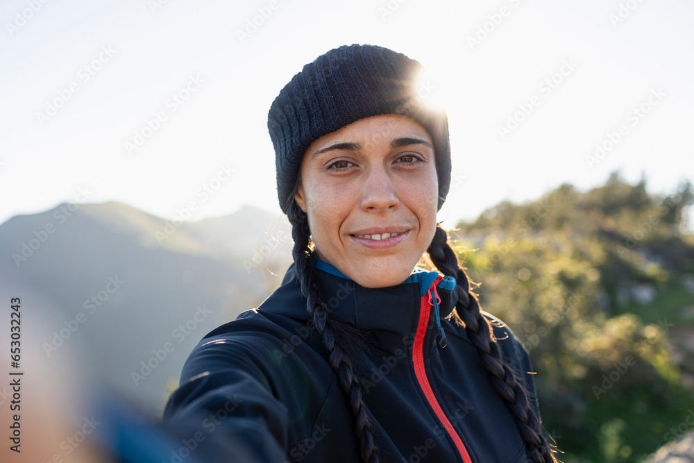 A young woman, mountaineer, warm from the cold, takes a selfie while enjoying the scenery and nature A young woman, mountaineer, warm from the cold, takes a selfie while enjoying the scenery and nature