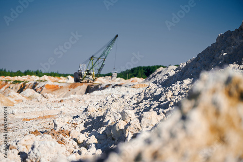 Walking excavator operates near piles row in mining pit
