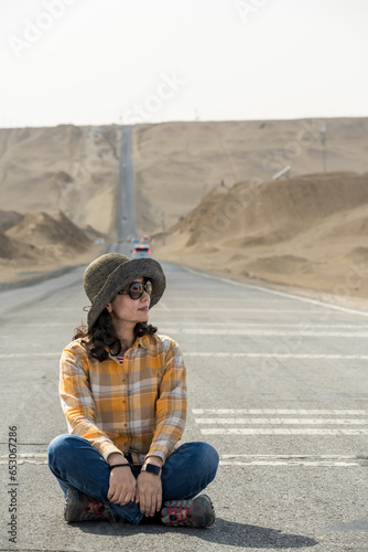 A traveler sits on desert road. © imphilip