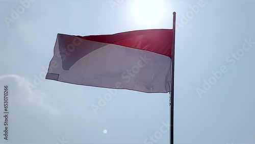 Indonesian national flag flying high with blue sky and bright clouds