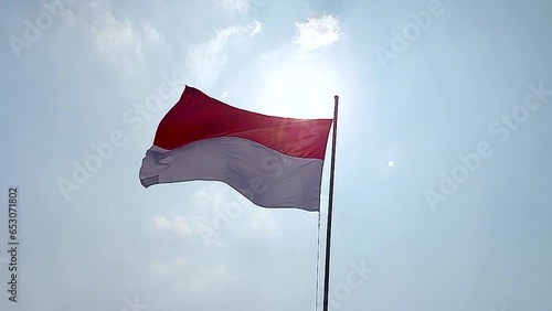 Indonesian national flag flying high with blue sky and bright clouds