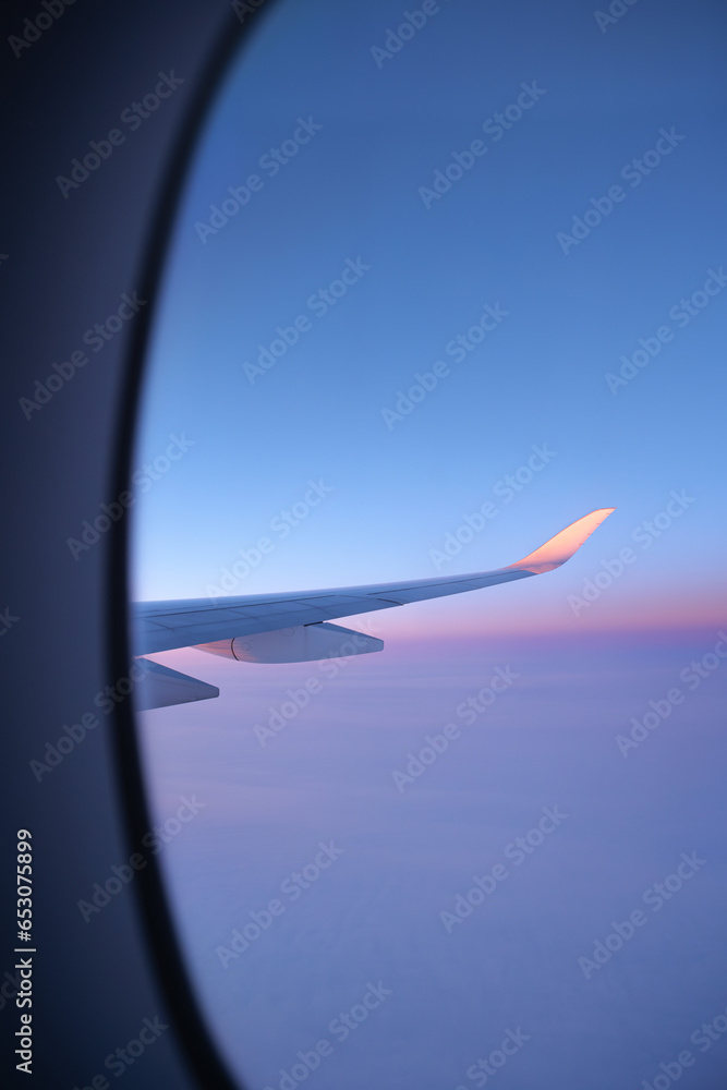An airplane wing seen through an oval window. View on a North Pole snowy landscape while flying the polar route. Vanilla sky. An airplane wing seen through an oval window. View on a North Pole snowy landscape while flying the polar route. Vanilla sky.
