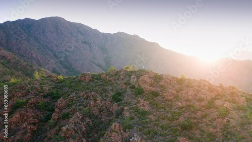 Scenic flight around the man staying on the mountain peak at beautiful sunrise photo