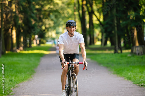 Young man in protective hemlet riding a bike in a park