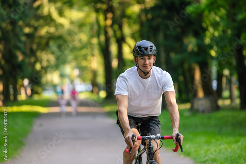 Young man in protective hemlet riding a bike in a park