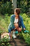 Sitting and working. Beautiful young woman is gardening