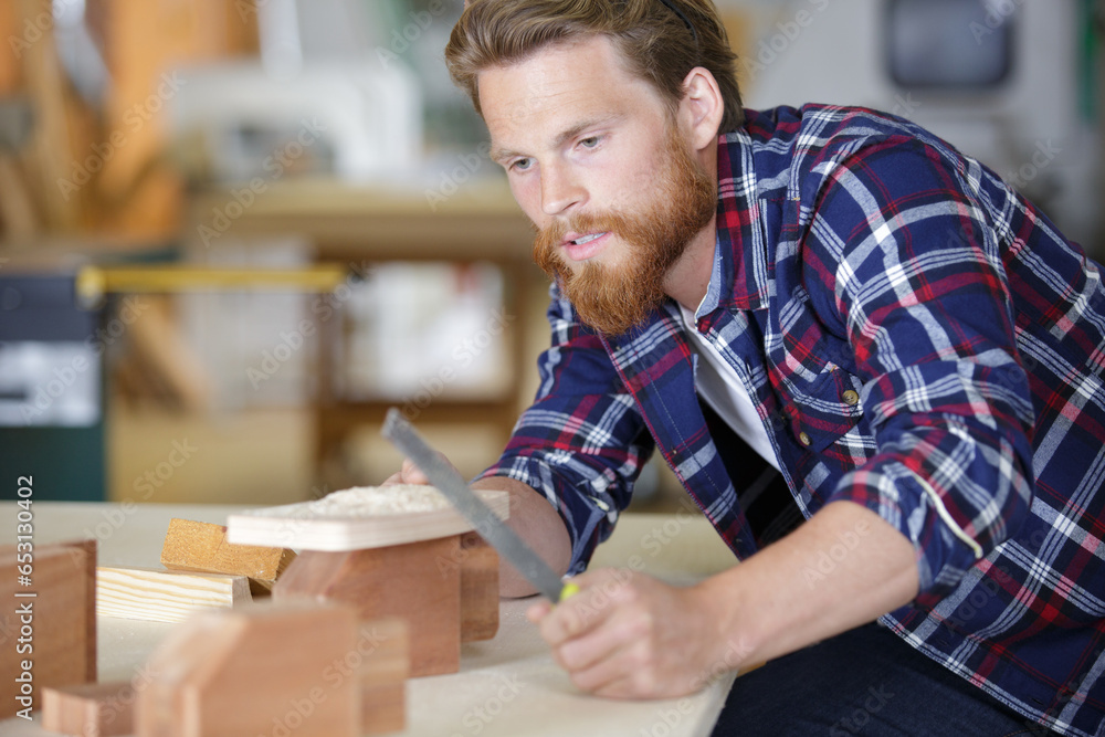 Obraz premium man sanding a wood with sander in a workshop