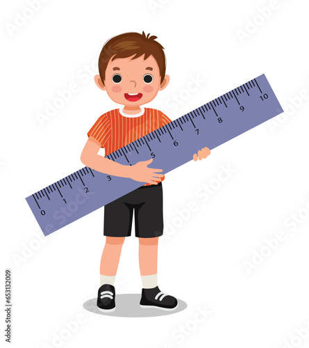 Cute little boy student holding big ruler