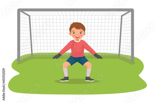 Cute little boy playing soccer ball as a goalkeeper standing in pose at the goal