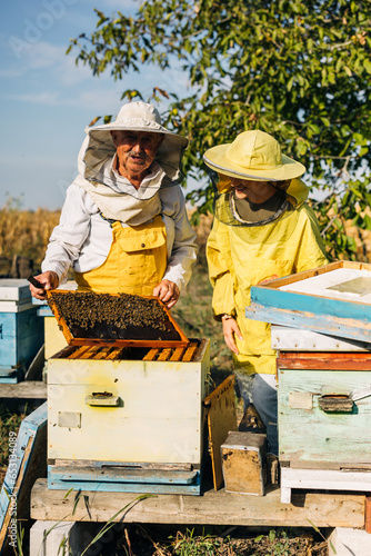 Happy grandfather enjoys beekeeping with his granddaughter.