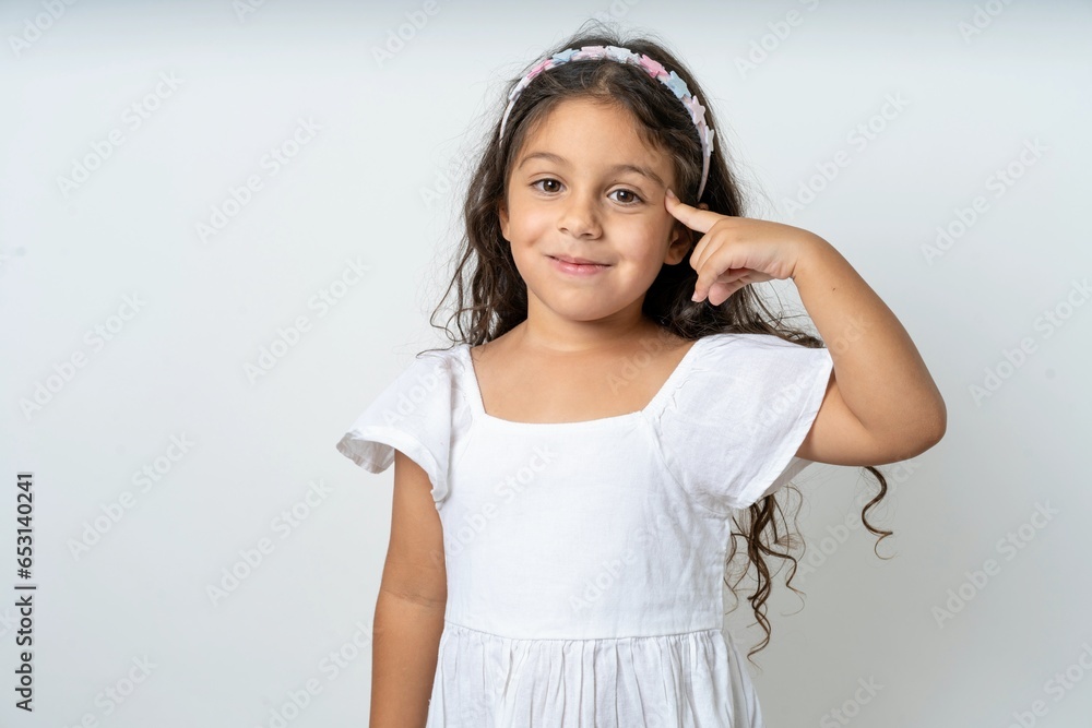 beautiful kid girl wearing dress tries to memorize something, keeps fore finger on temple, reminds information for exam, beautiful kid girl wearing dress tries to memorize something, keeps fore finger on temple, reminds information for exam,
