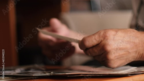 the hands of an old man are holding old family black and white photos. feelings of nostalgia, memories, emotions of an elderly person. old father looking at home photo archive