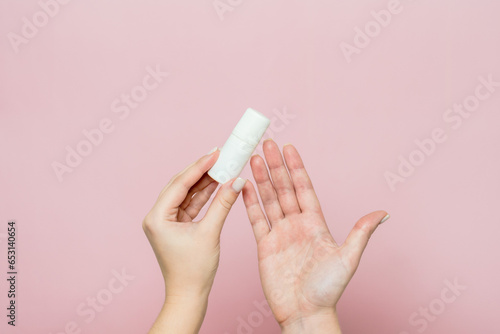 White bottle, drops for eye, nose or ear in hand on pink background. Pharmaceutical product.