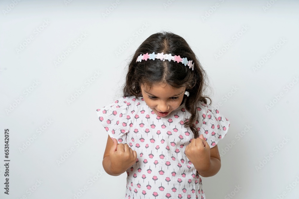 beautiful kid girl wearing dress very happy and excited doing winner gesture with arms raised, smiling and screaming for success. Celebration concept. beautiful kid girl wearing dress very happy and excited doing winner gesture with arms raised, smiling and screaming for success. Celebration concept.