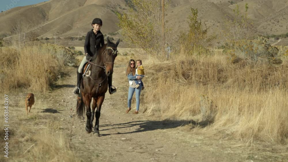 Jockey On Horseback Rides Down Trail While Mother and Daughter Wave Goodbye - Slow Motion Jockey On Horseback Rides Down Trail While Mother and Daughter Wave Goodbye - Slow Motion