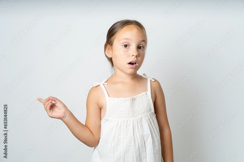 Emotive beautiful kid girl wearing white dress keeps jaw dropped from shock demonstrates amazing promo points right on blank space demonstrates big shopping sale. Advertisement Emotive beautiful kid girl wearing white dress keeps jaw dropped from shock demonstrates amazing promo points right on blank space demonstrates big shopping sale. Advertisement