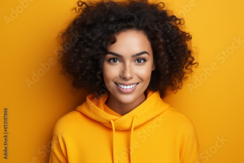 Portrait charming gorgeous happy cheerful positive joyful smiling African American young woman lady model standing teen girl student looking camera enjoying yellow plane background makeup fashion © Yuliia