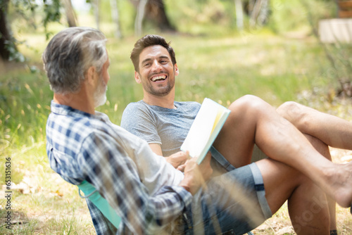 two jovial men relaxing in the countryside with a book