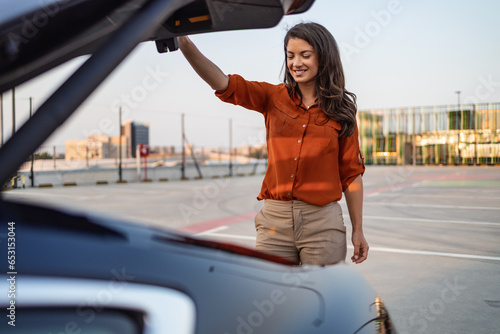 Woman closing car trunk parked. One woman Caucasian female standing by the back trunk of her car on the parking lot photo
