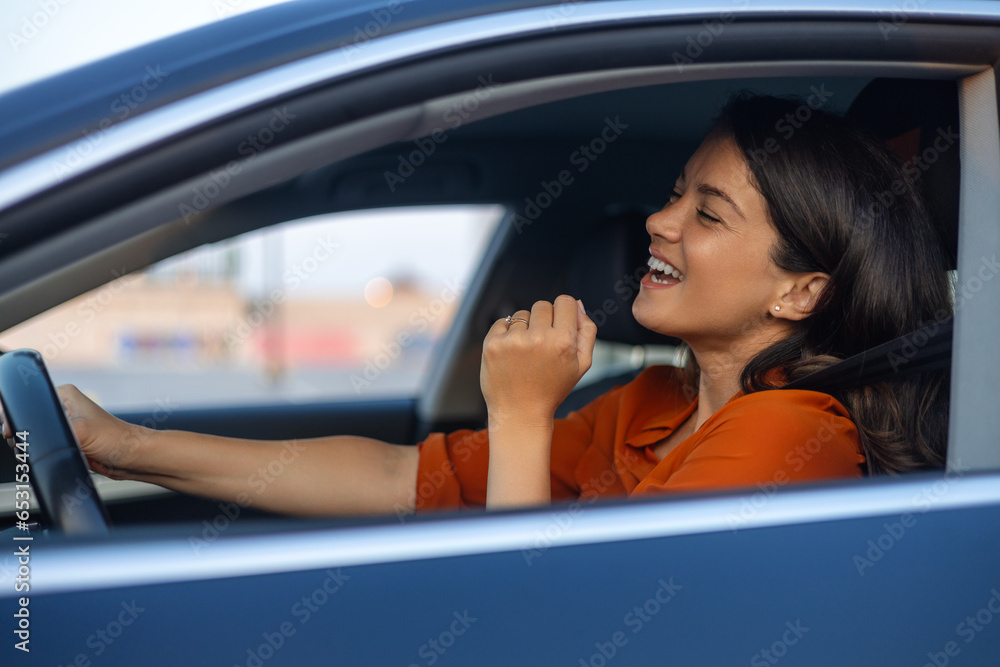 Photo of positive cheerful girl funky driver rider enjoy drive ride car under pop star hits playlist music try dance raise hands in city center