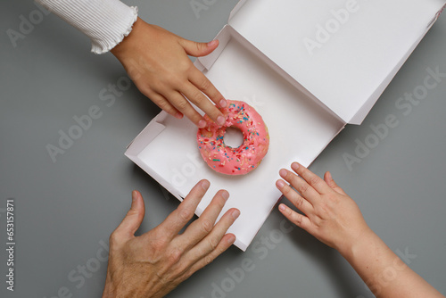 Family with donut. Hands and sweet  dessert closeup, top view photo