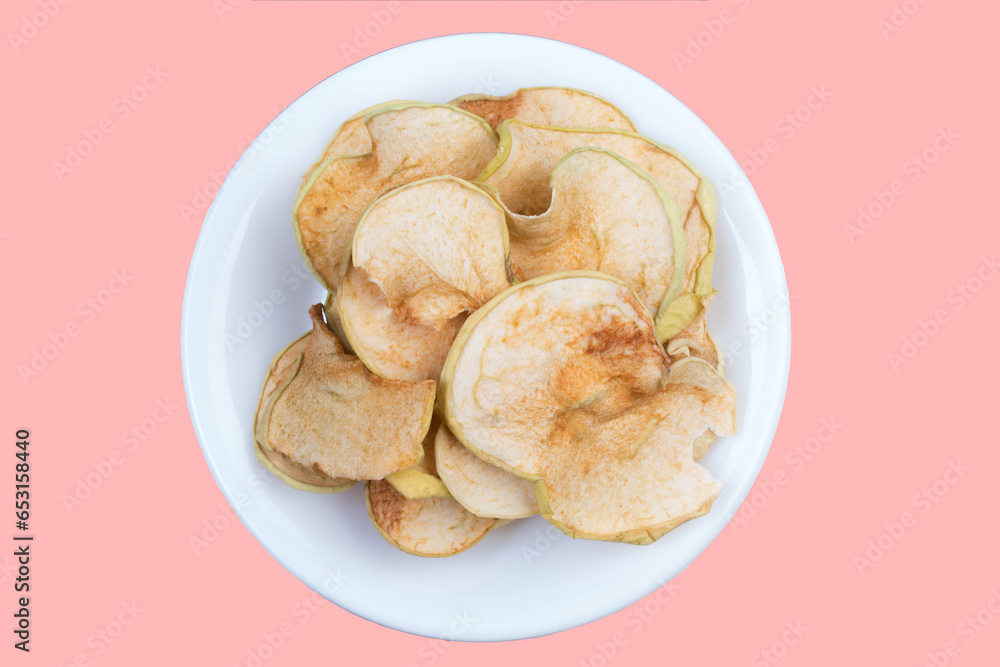 Sliced, dried apples in a plate isolated on pink background. Homemade organic apple.