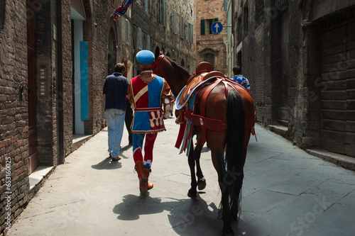 Vista de un caballo participante y su jinete en una calle de Siena el día de la carrera del Palio, Toscana, Italia.
