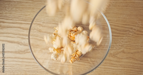 Popcorn falls into the plate, top view. Cheese popcorn filling a glass plate.