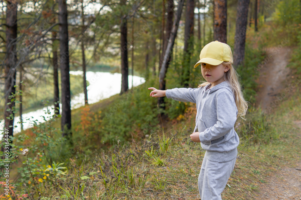 A little cute girl is walking in a beautiful forest in the autumn, she discovered a river and shows it to her mother A little cute girl is walking in a beautiful forest in the autumn, she discovered a river and shows it to her mother