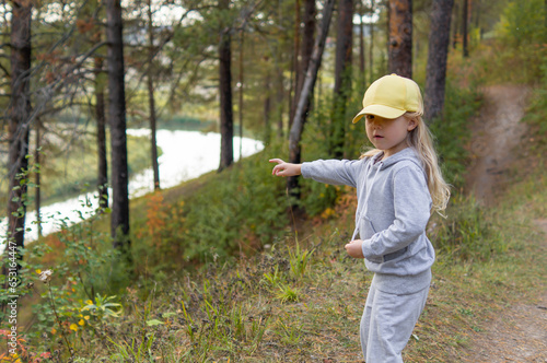 A little cute girl is walking in a beautiful forest in the autumn, she discovered a river and shows it to her mother